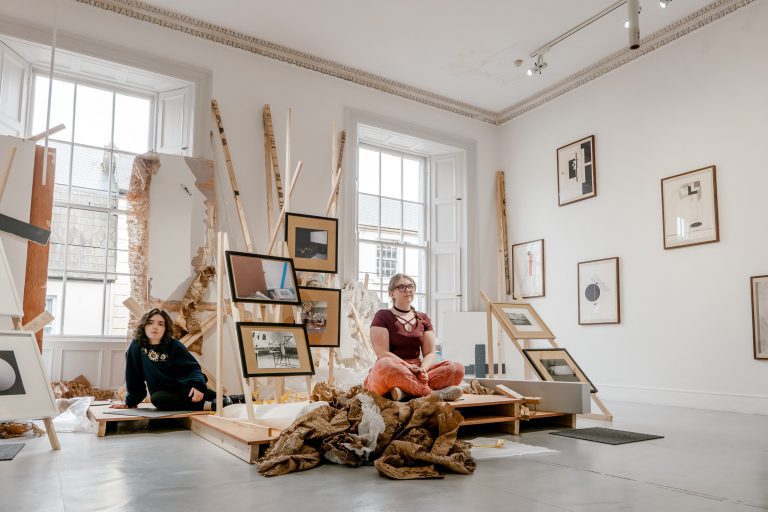 Two young people sat within art installation.