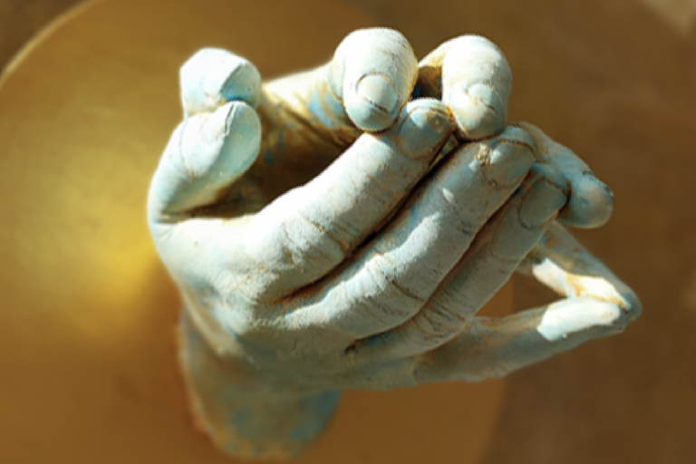 A image of ceramic hands with a gold coloured background
